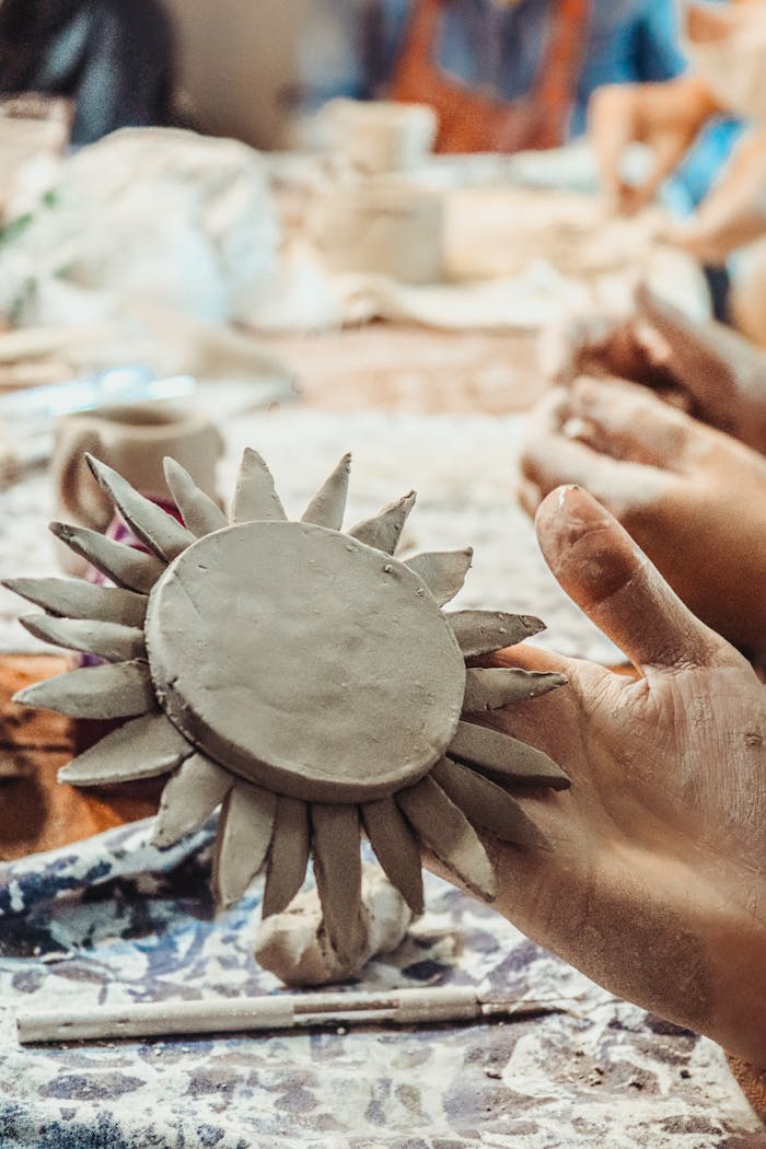 Clay sun sculpture being handcrafted by artisans. Close-up in pottery workshop.